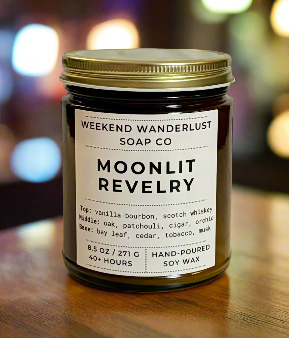 Candle jar labeled 'Moonlit Revelry' from Weekend Wanderlust Soap Co with a blurred lights background