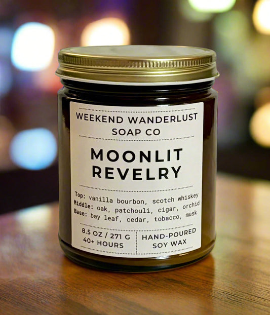 Candle jar labeled 'Moonlit Revelry' from Weekend Wanderlust Soap Co with a blurred lights background