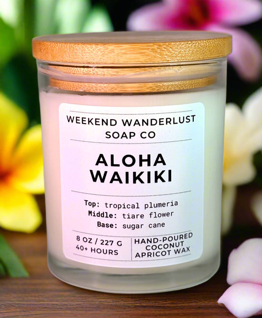 Candle with 'Weekend Wanderlust Soap Co' label and tropical flower background