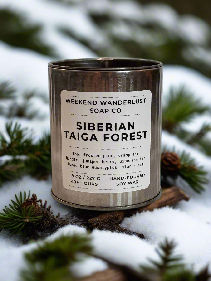 Candle labeled 'Siberian Taiga Forest' by Weekend Wanderlust Soap Co. on a snowy background with pine branches.