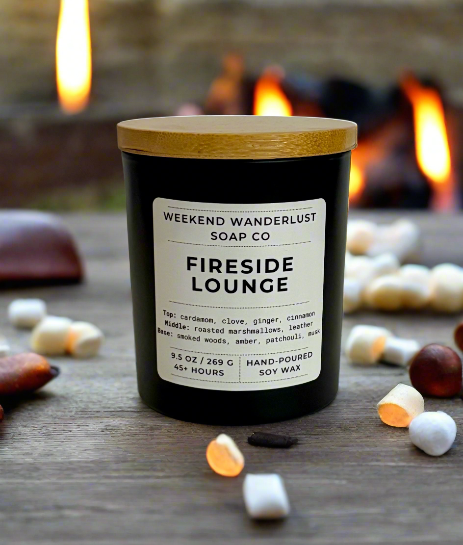 Candle labeled 'Fireside Lounge' from Weekend Wanderlust Soap Co. with a fireplace in the background.