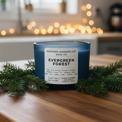 Blue candle labeled 'Evergreen Forest' on a wooden surface with Christmas decorations.