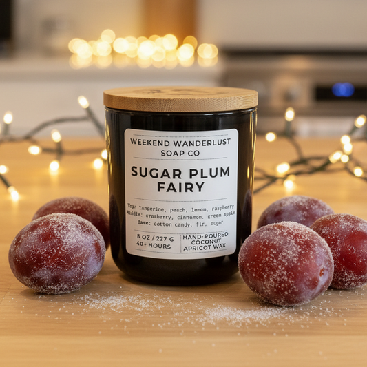 Candle labeled 'Sugar Plum Fairy' from Weekend Wanderlust Soap Co on a wooden surface with decorative lights in the background.