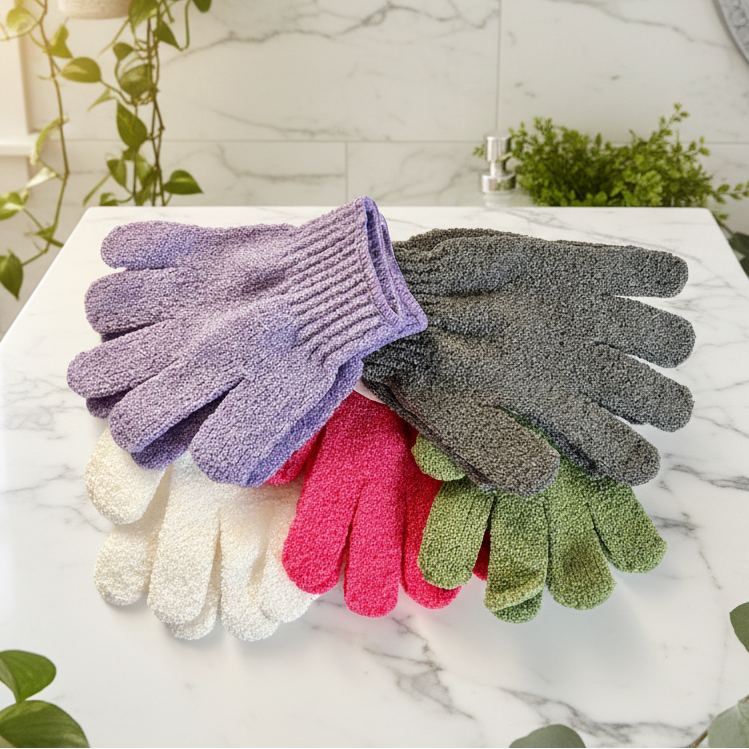 Set of colorful exfoliating gloves on a marble surface with plants and a sink in the background.