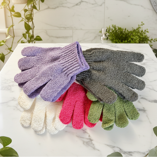 Set of colorful exfoliating gloves on a marble surface with plants and a sink in the background.