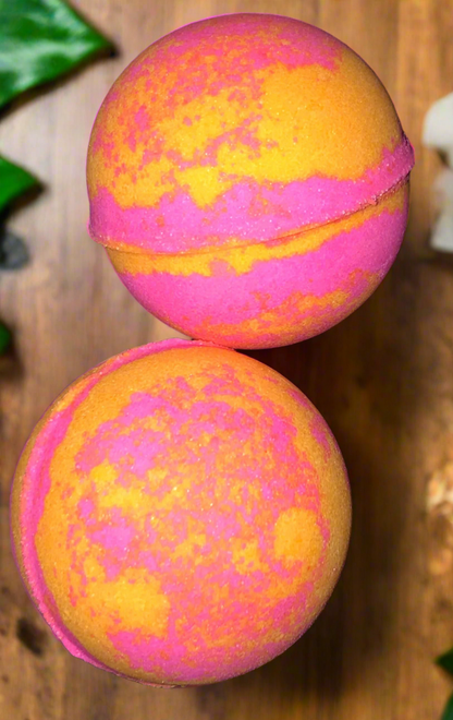 Two colorful bath bombs with pink and orange marbled pattern on a wooden surface.